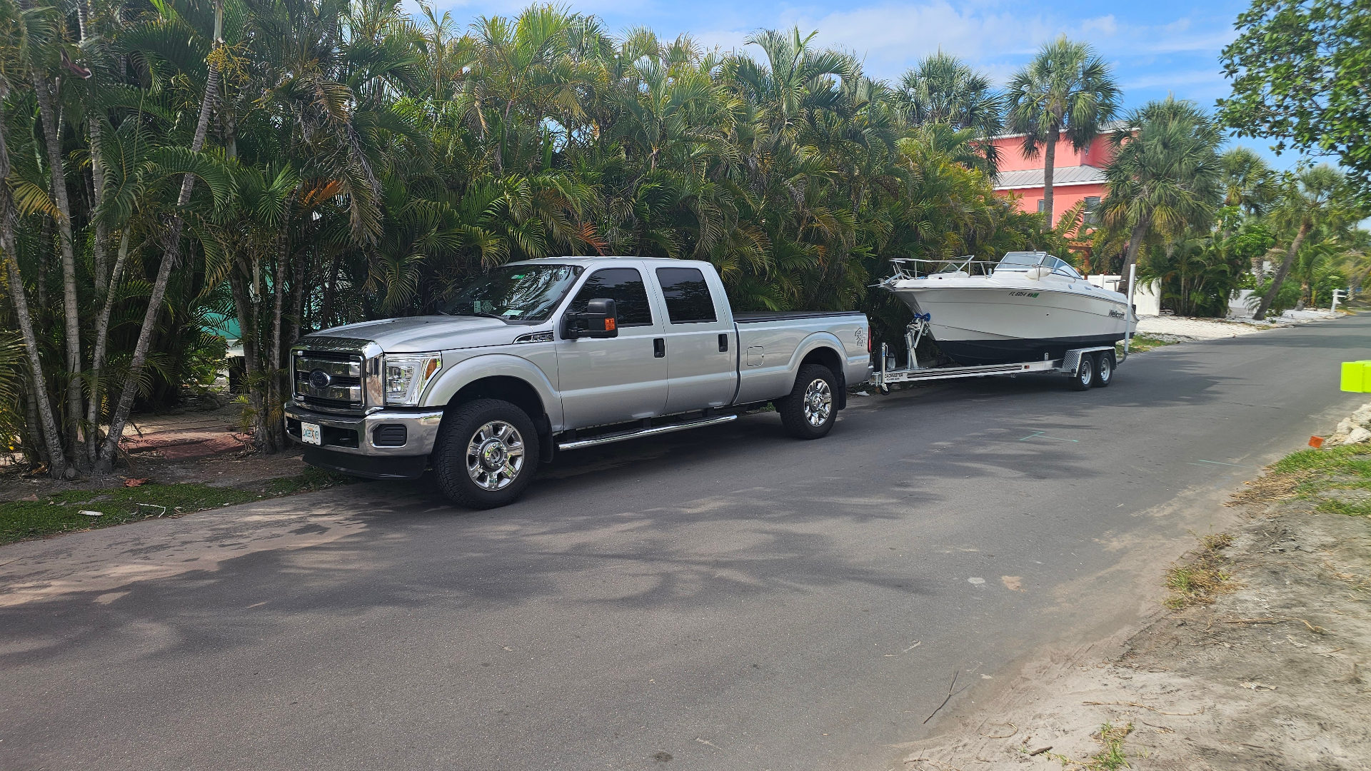 Truck towing a boat down a palm-lined Longboat Key street